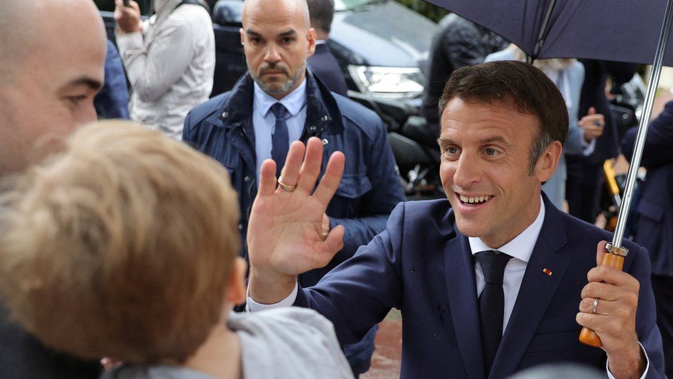 Президент Франции Эммануэль Макрон приветствует сторонников, уходя после голосования во втором туре парламентских выборов во Франции, на избирательном участке в Ле-Туке-Пари-Плаж, Франция, 19 июня 2022 г.