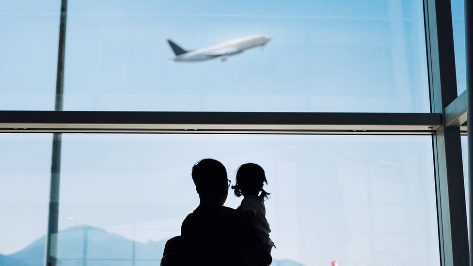 A silhouette of a man and a child watching a plane