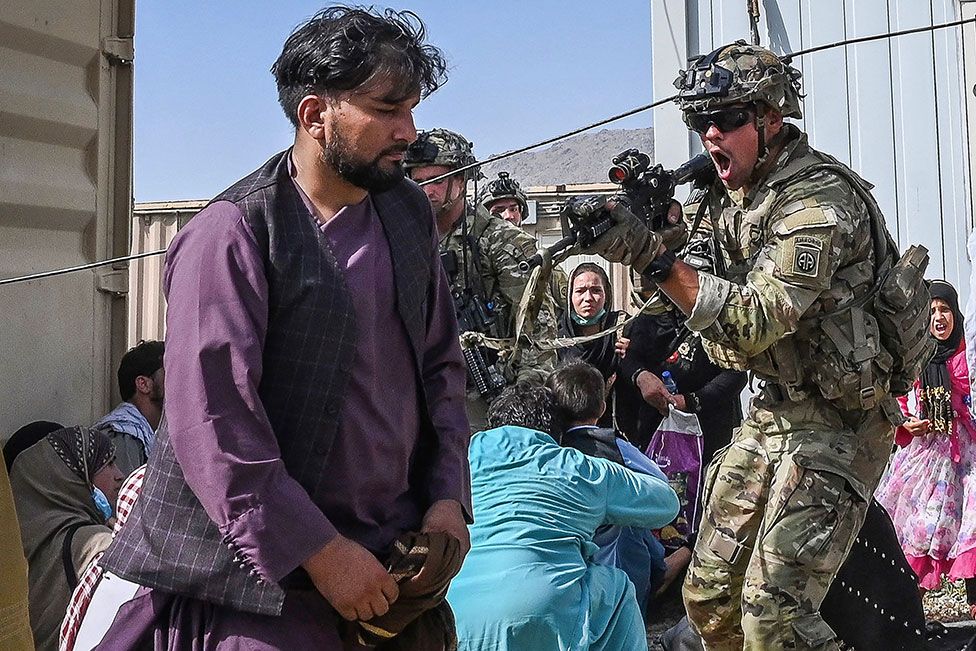 Американский солдат направляет пистолет в сторону афганского пассажира в аэропорту Кабула в Кабуле 16 августа 2021 года
