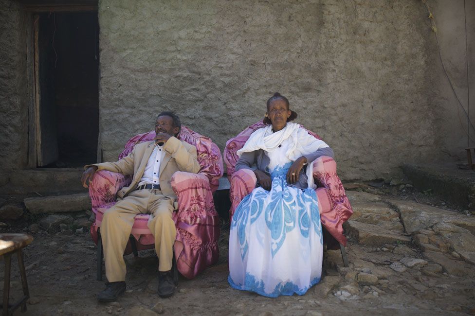 Two people sitting outside their home