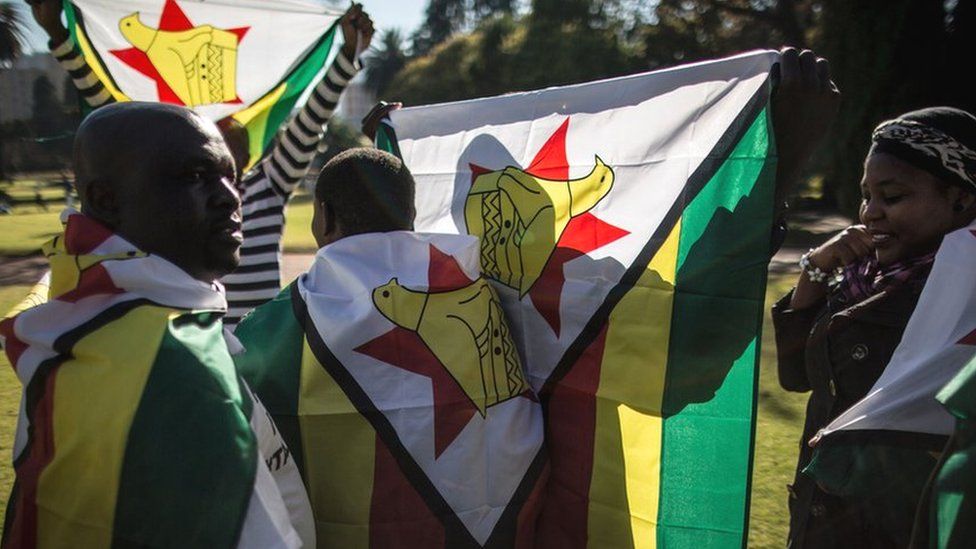 A Zimbabwean 'myflag' activist draped in their national flag gather in Pretoria on 14 July 2016 prior to a march to the Zimbabwean embassy.