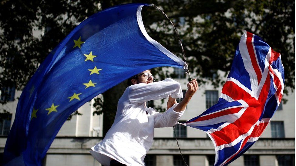 Мужчина машет флагами ЕС и Союза в Вестминстере в Лондоне
