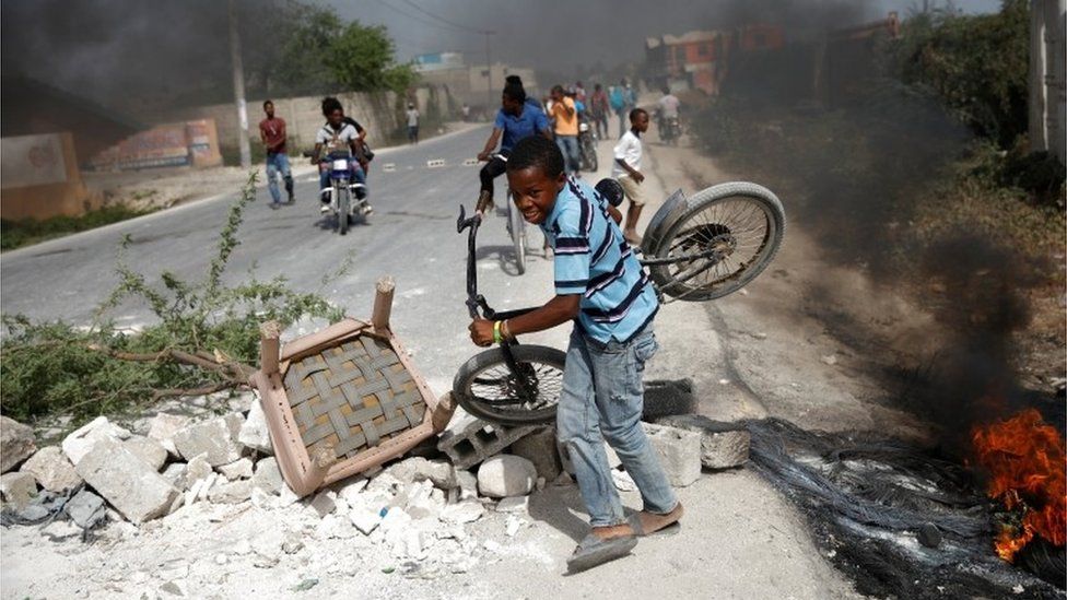 A boy carrying his bicycle passes through a barricade on the outskirts of Croix-des-Bouquets, Haiti, July 8, 2018.