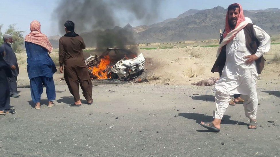 Pakistani local residents gathering around a destroyed vehicle hit by a drone strike in which Afghan Taliban Chief Mullah Akhtar Mansour was believed to be travelling
