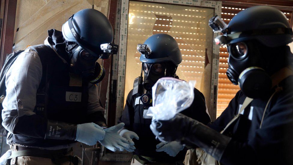 A U.N. chemical weapons expert, wearing a gas mask, holds a plastic bag containing samples from one of the sites of an alleged chemical weapons attack in the Ain Tarma neighbourhood of Damascus in this August 29, 2013