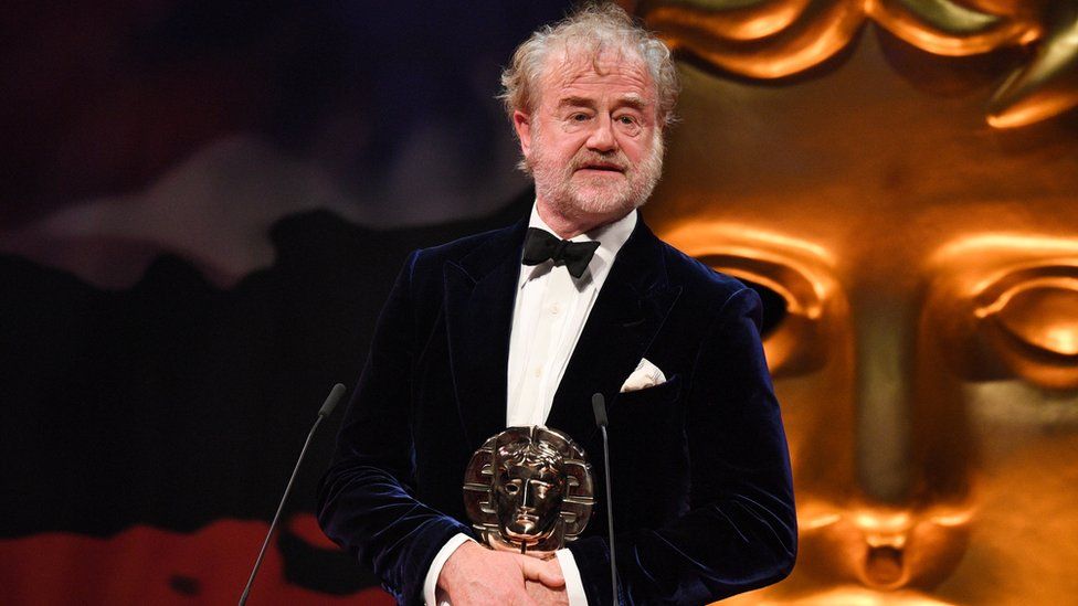 Owen Teale on stage holding award