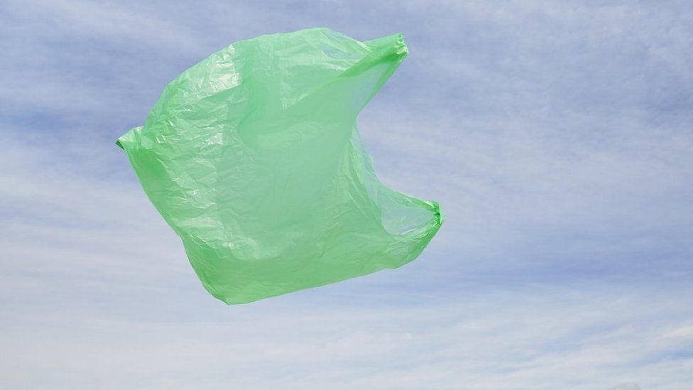 Green plastic bag floating in front of blue sky