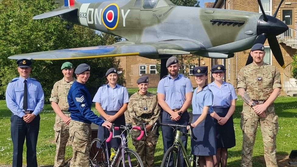 RAF Digby staff standing in front of a Lancaster bomber with two holding onto bikes