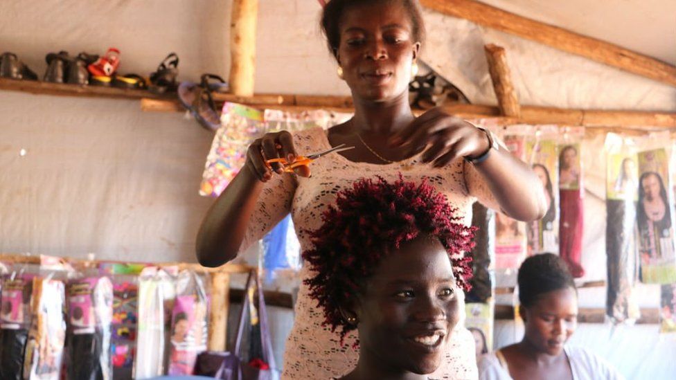 Refugee entrepreneur Penina cutting hair
