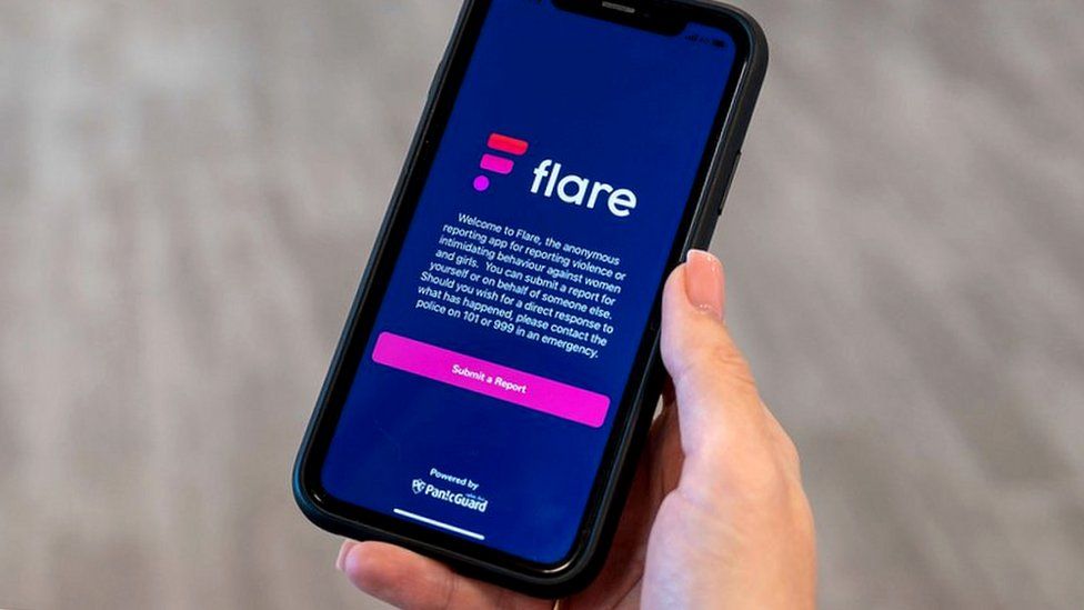 Woman holding a phone showing the Flare Report app on screen