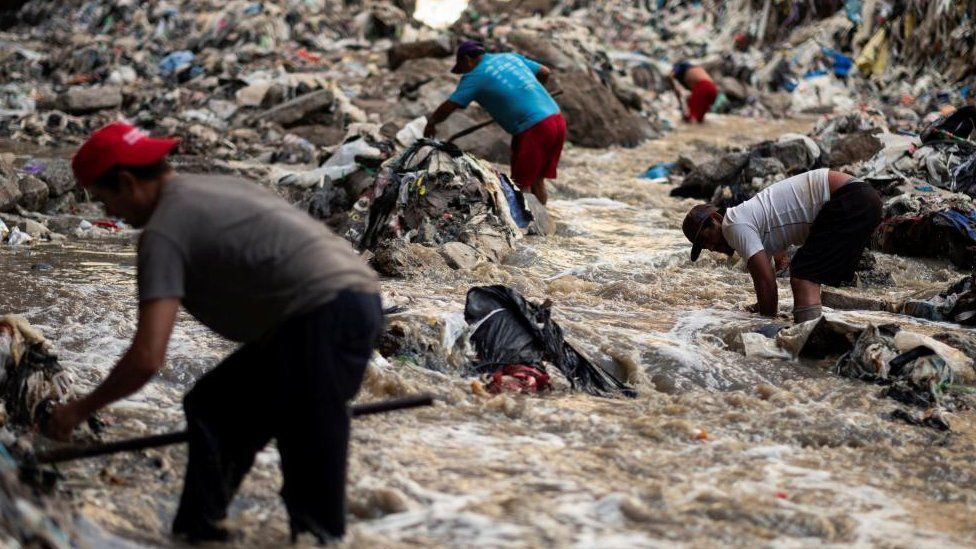 Men search for scrap metal in the polluted waters of the Las Vacas river