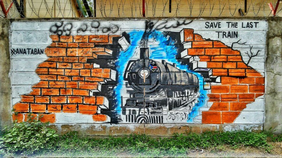 A picture of a train approaching a brick wall is painted on a wall