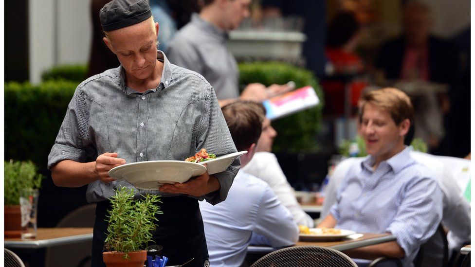 Waiter clearing an outdoor table at a restaurant