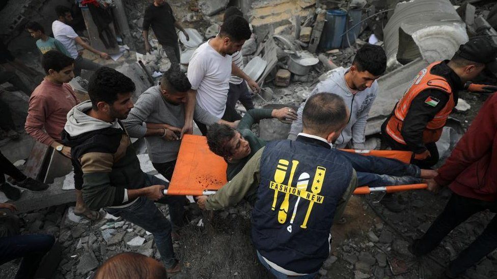 Palestinians recover a wounded person from the rubble of a destroyed house following Israeli airstrikes, in Deir Al Balah, central Gaza Strip, 8 December 2023