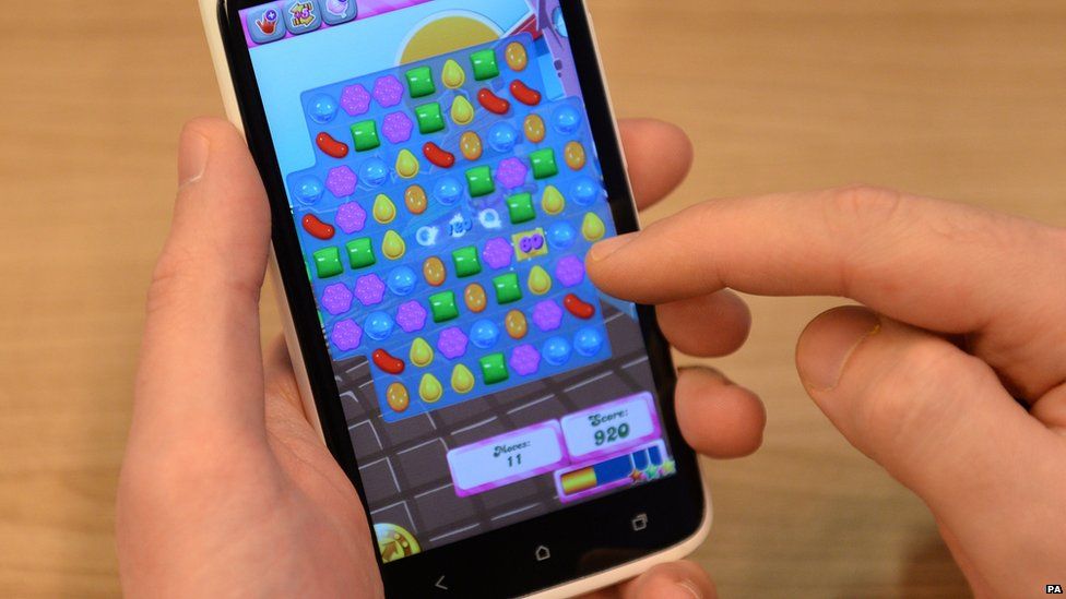 Hands holding a phone with Candy Crush loaded on it