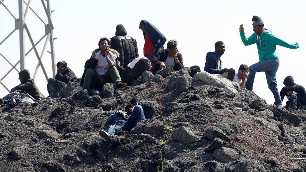 Migrants gather on a heap of loose earth near the former "jungle" in Calais, France, June 1, 2017.