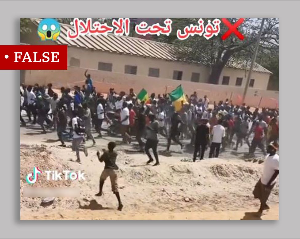 Screengrab of video showing protesters along a street, some waving Senegalese flags