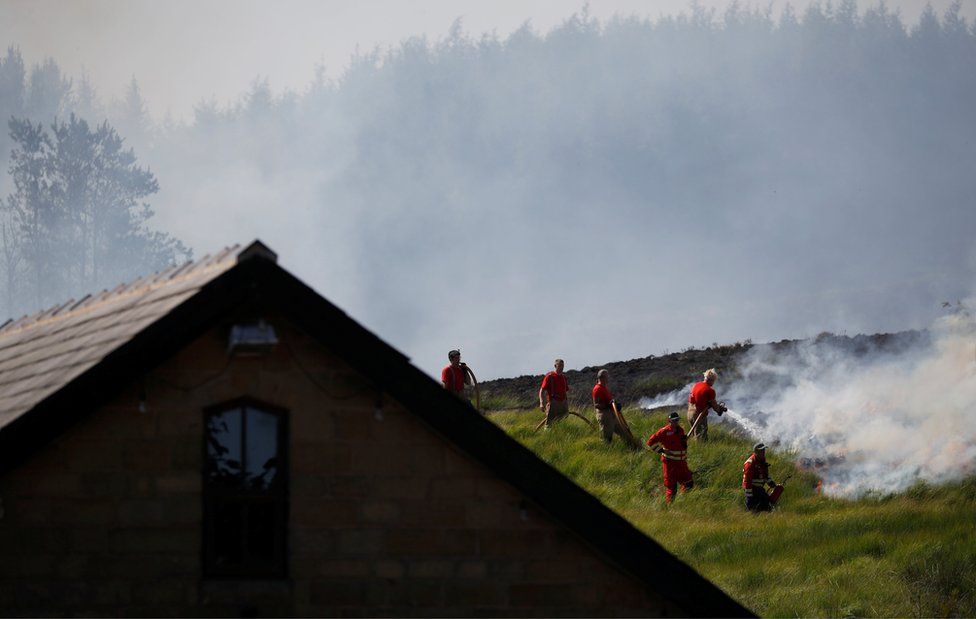 Fire fighters tackle a moorland fire near a building at Winter Hill, near Rivington, on 1 July 2018.