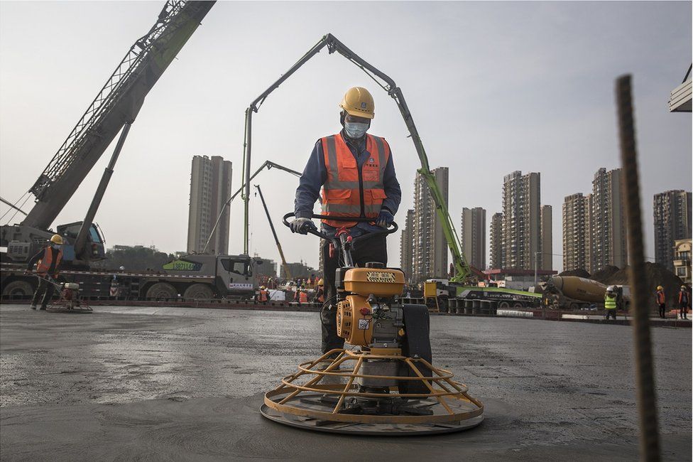 A construction worker is pictured amidst heavy machinery on the site of Huoshenshan hospital, under construction