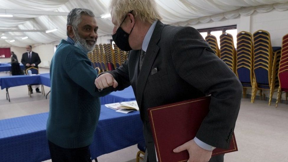 Prime Minister Boris Johnson elbow bumps with community leader Rafik Dabhad