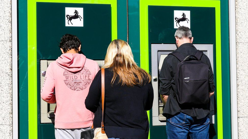 Customers queuing at an ATM