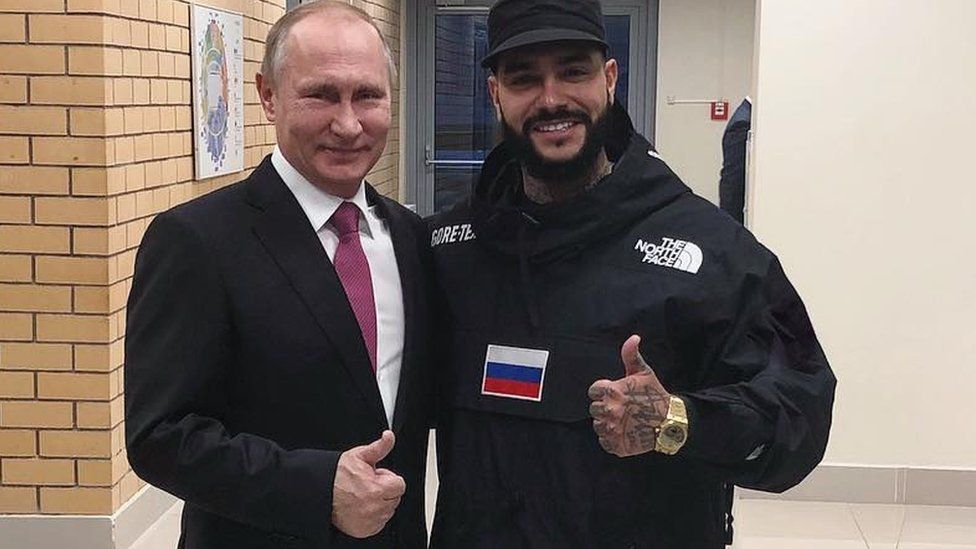 Vladimir Putin and Timati stand side-by-side, giving the thumbs-up gesture