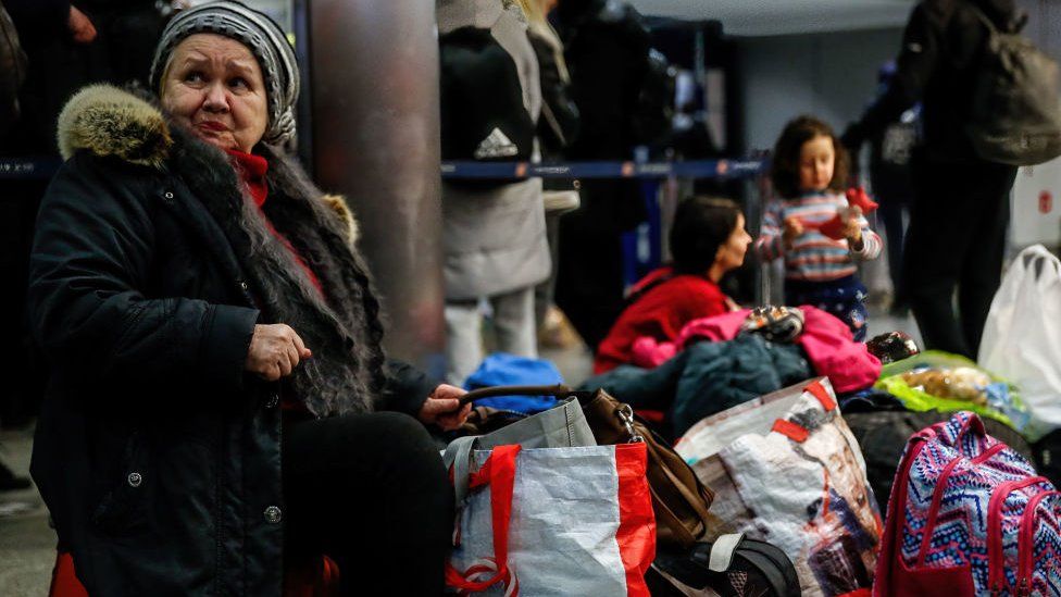 A Ukrainian refugee rests on her luggage after arriving at the main railway station in Krakow as more than million people already fled Ukraine for Poland.