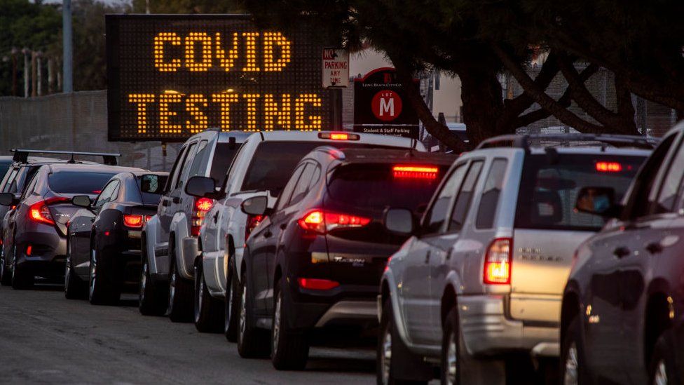 A long line of vehicles line up to take Covid-19 tests at dusk at Long Beach City College-Veterans Memorial Stadium in December
