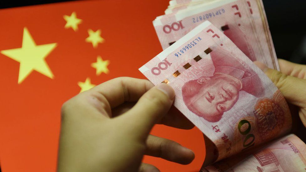 A man counting 100 RMB notes with the Chinese flag in the background