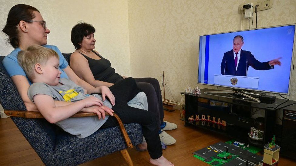 Una famiglia guarda la trasmissione televisiva del discorso annuale del Presidente russo Vladimir Putin sullo stato della nazione a Mosca il 21 febbraio 2023