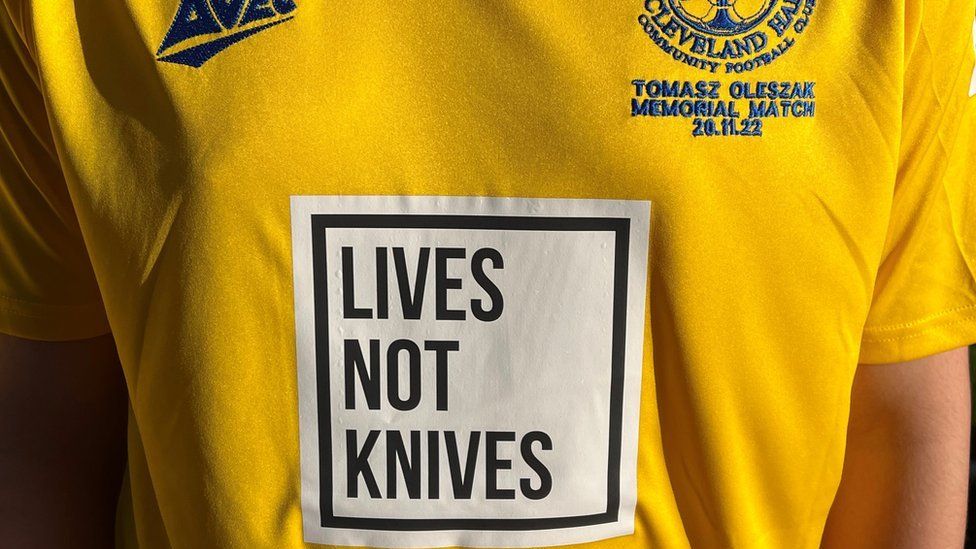 A close up of a yellow football shirt with the lives not knives message