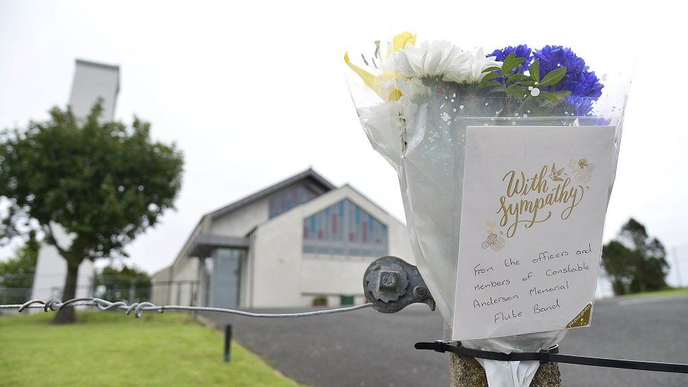 Flowers left at the scene were a man in his 30s has died after an accident while helping to build a bonfire at a site in County Antrim, police have said