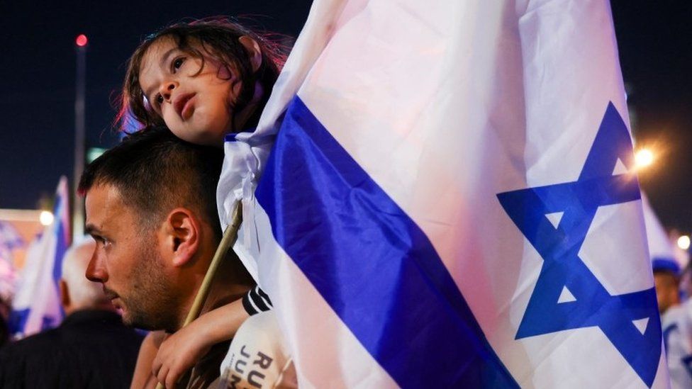 A man carries a child with Israeli flag in Tel Aviv, Israel. Photo: 11 March 2023
