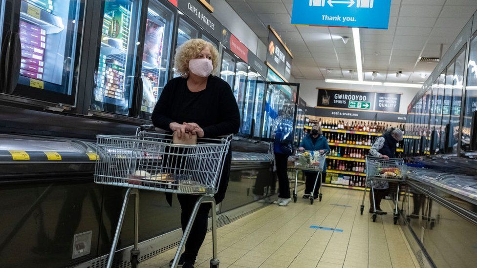 Женщина в маске делает покупки в супермаркете Aldi в Уэльсе