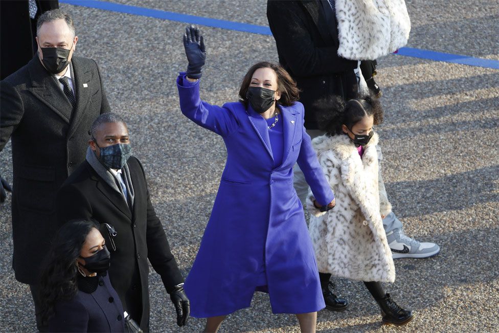 Vice President Kamala Harris waves ashe walks with Second Gentleman Doug Emhoff