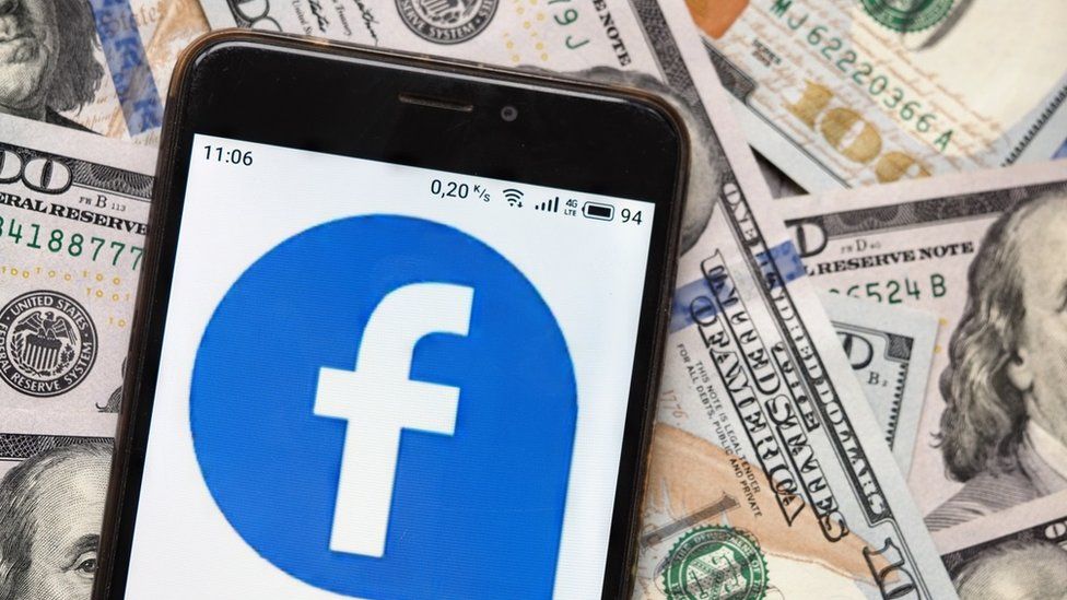 Facebook logo on phone with dollar bills in background