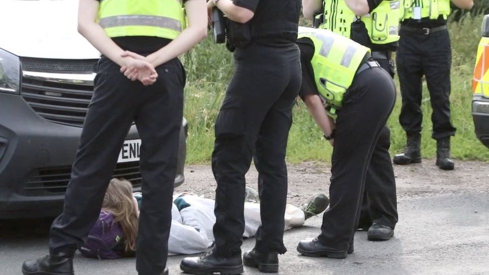 A protester being spoken to by police at MBR Acres in Sawtry Way, Wyton