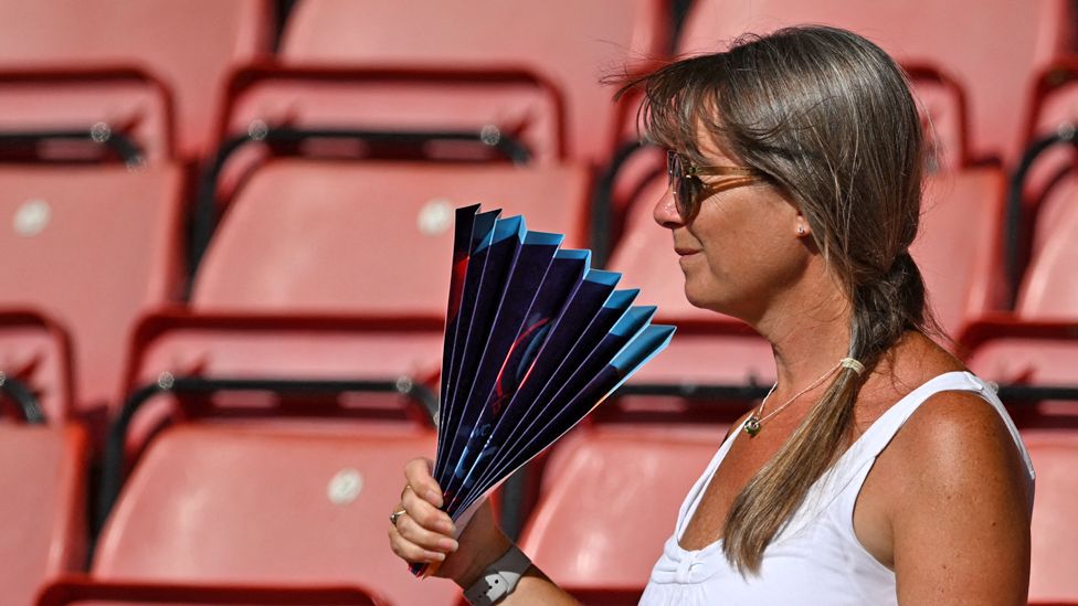 Woman with fan tries to stay cool