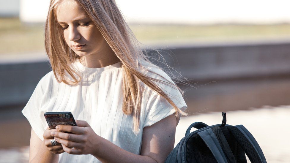 A stock photo of a 15-year-old looking at her phone