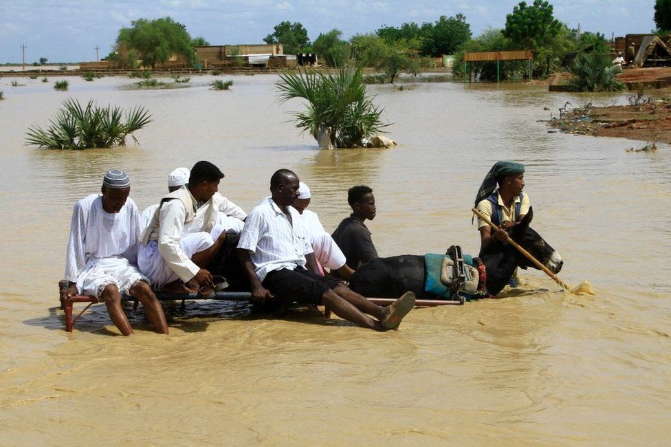 Sudanese cross a flooded road in the town of Iboud, in al-Gezira state.