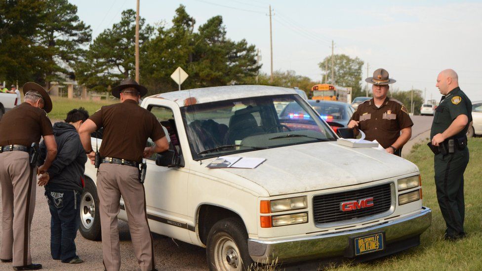 Oklahoma Highway Patrol troopers Keith Teel, left, and Brian Bagwell arrest a woman on suspicion of driving under the influence after she allegedly fell out of a moving pickup truck in Ada, Okla.