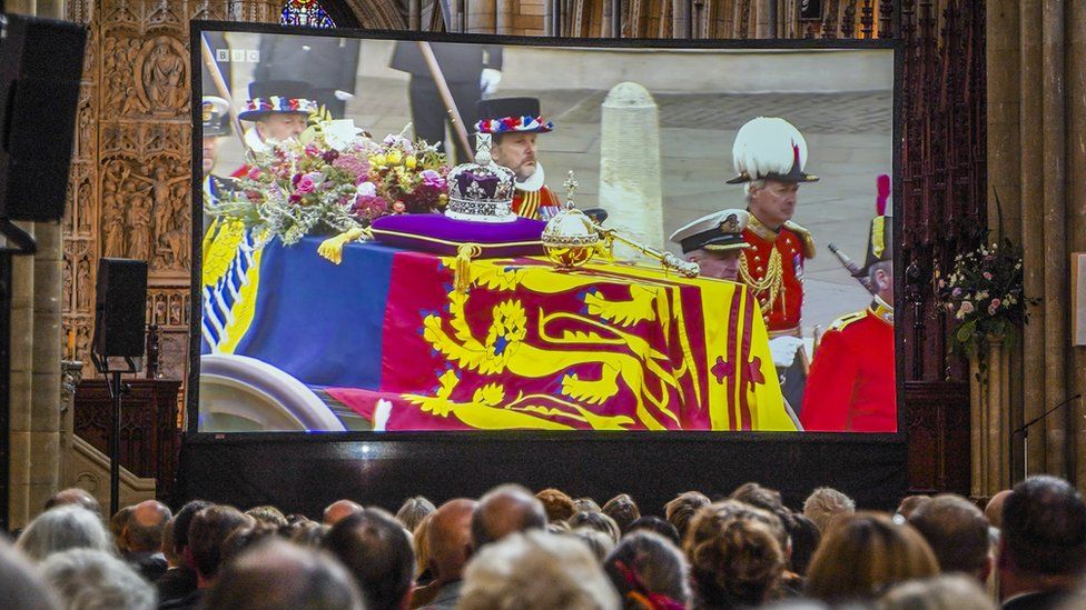 Представители общественности собираются, чтобы посмотреть на большом экране прямую трансляцию BBC TV похорон королевы Елизаветы II в соборе Труро