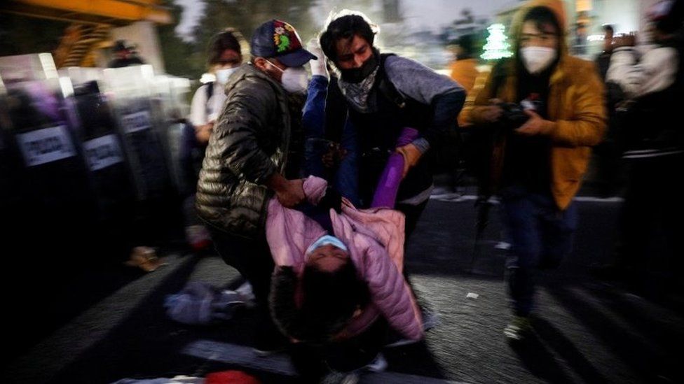 Members of the migrant caravan carry a fellow migrant who was injured when a crowd pushed against the police, who are preventing them from passing on the Mexico-Puebla highway, in Los Reyes La Paz, Mexico, December 12, 2021