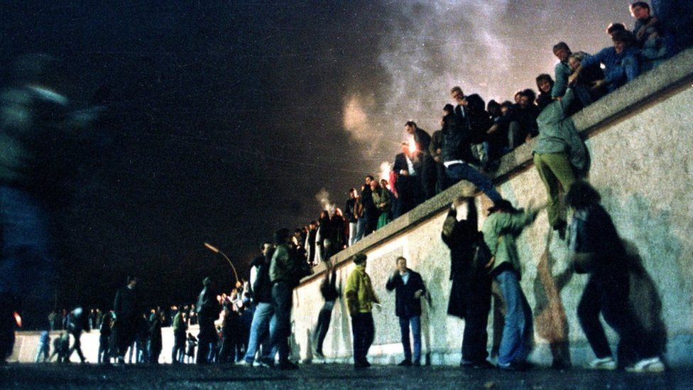 East Germans citizens climb the Berlin Wall at the Brandenburg Gate after the opening of the East German border was announced in Berlin, in this file picture taken 9 November 1989