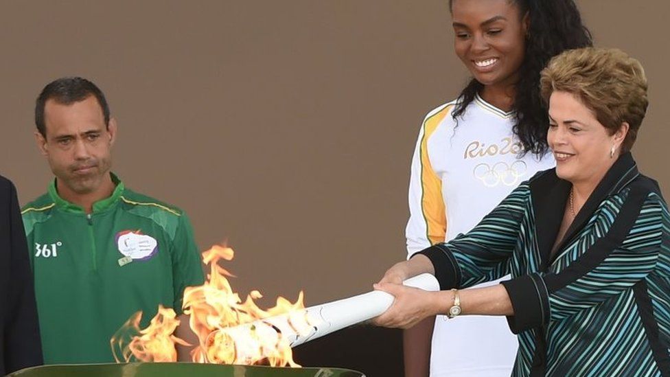 Brazilian President Dilma Rousseff (R) hands the Olympic torch to Brazilian volleyball player Fabiana Claudino at Planalto Palace in Brasilia following the flame"s arrival in Brazil on May 3, 2016, to begin its journey across the country before the start of the 2016 Olympic Games on August 5