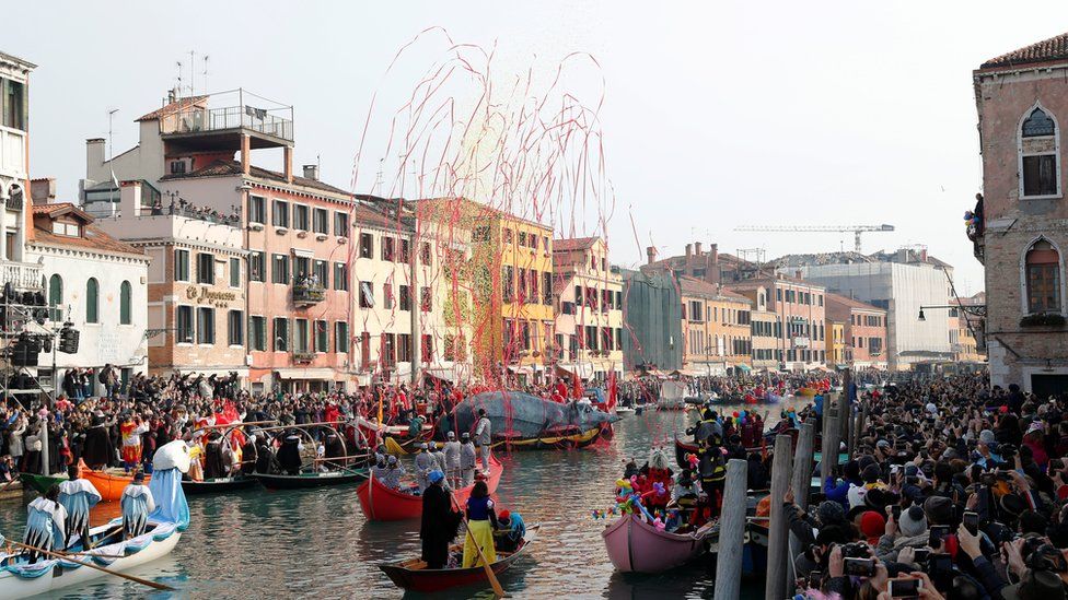 Venetians row during the masquerade parade on the Grand Canal during the Carnival in Venice