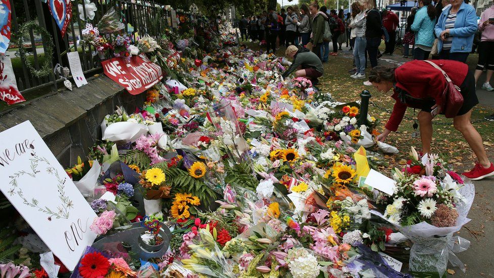 Residents look at flowers in tribute to victims in Christchurch on 18 March