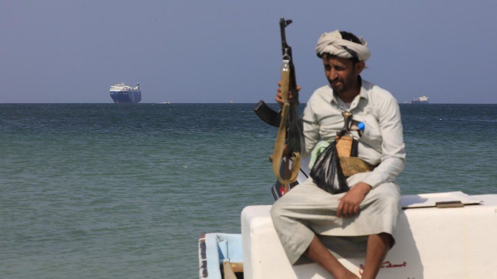 An armed Yemeni sits on a boat in front of the Galaxy Leader cargo ship, seized by the Houthis offshore of the Al-Salif port on the Red Sea in the province of Hodeidah, Yemen, 05 December 2023