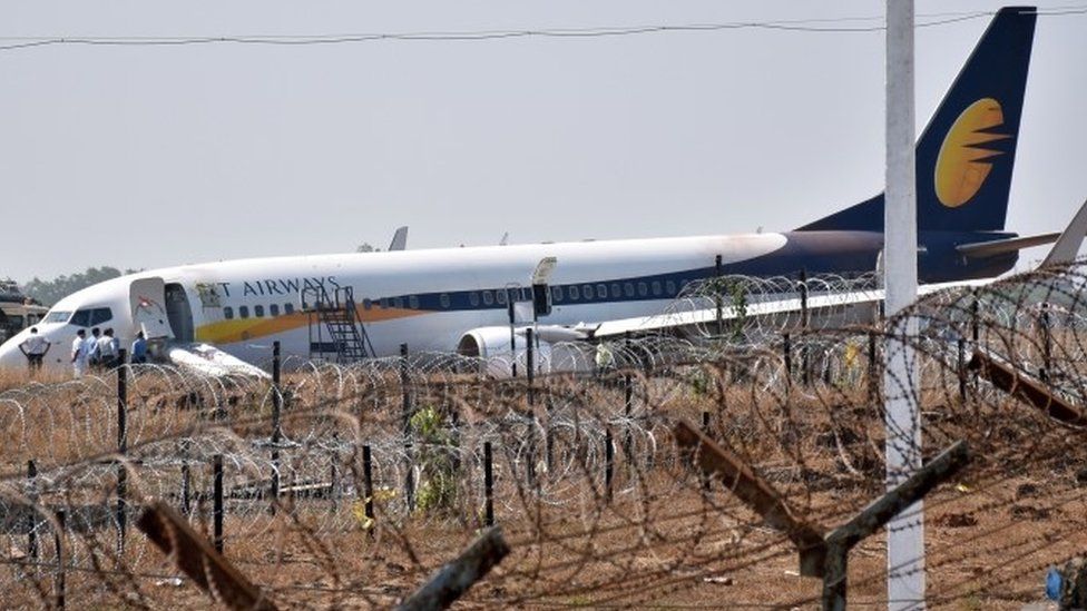 Indian officials gather beside a Jet Airways Boeing 737 aircraft after it skidded off the runway following an aborted take-off at the Goa Airport in Dabolim, in India's western state of Goa (27 December 2017)