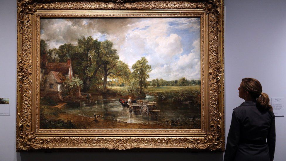 A V&A museum employee looking at John Constable's 1821 painting The Hay Wain